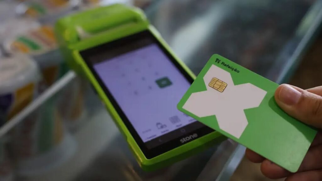 Cartão de vale-alimentação sendo utilizado em máquina de pagamento; novas regras do PAT entram em vigor.