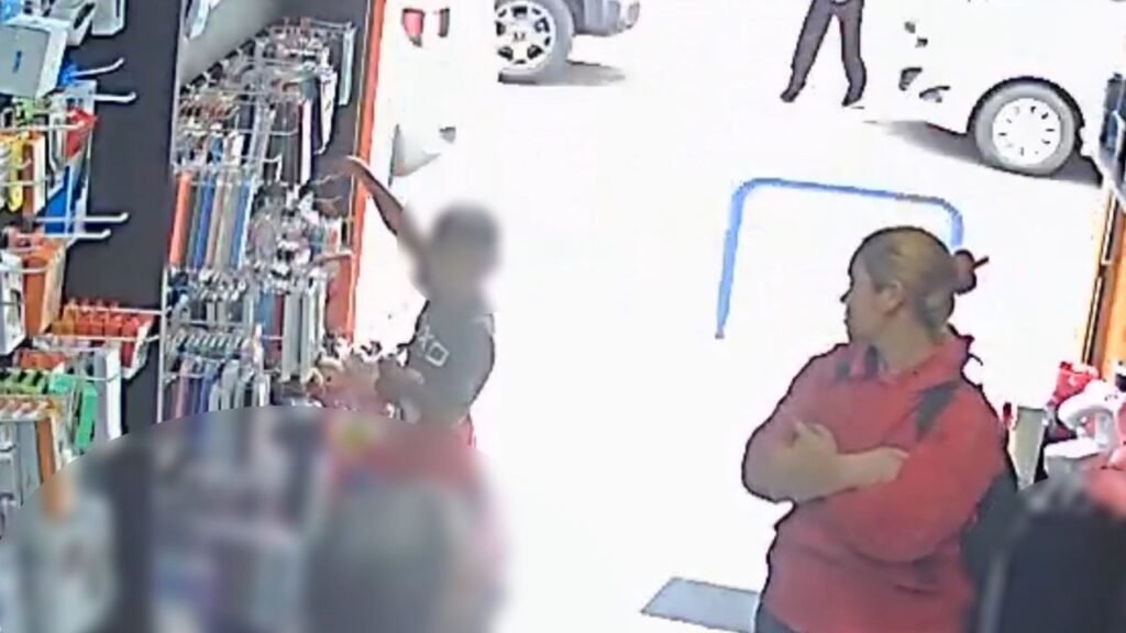 Câmera de segurança mostra mulher observando enquanto criança pega objetos expostos em loja no Centro de Guarapuava.