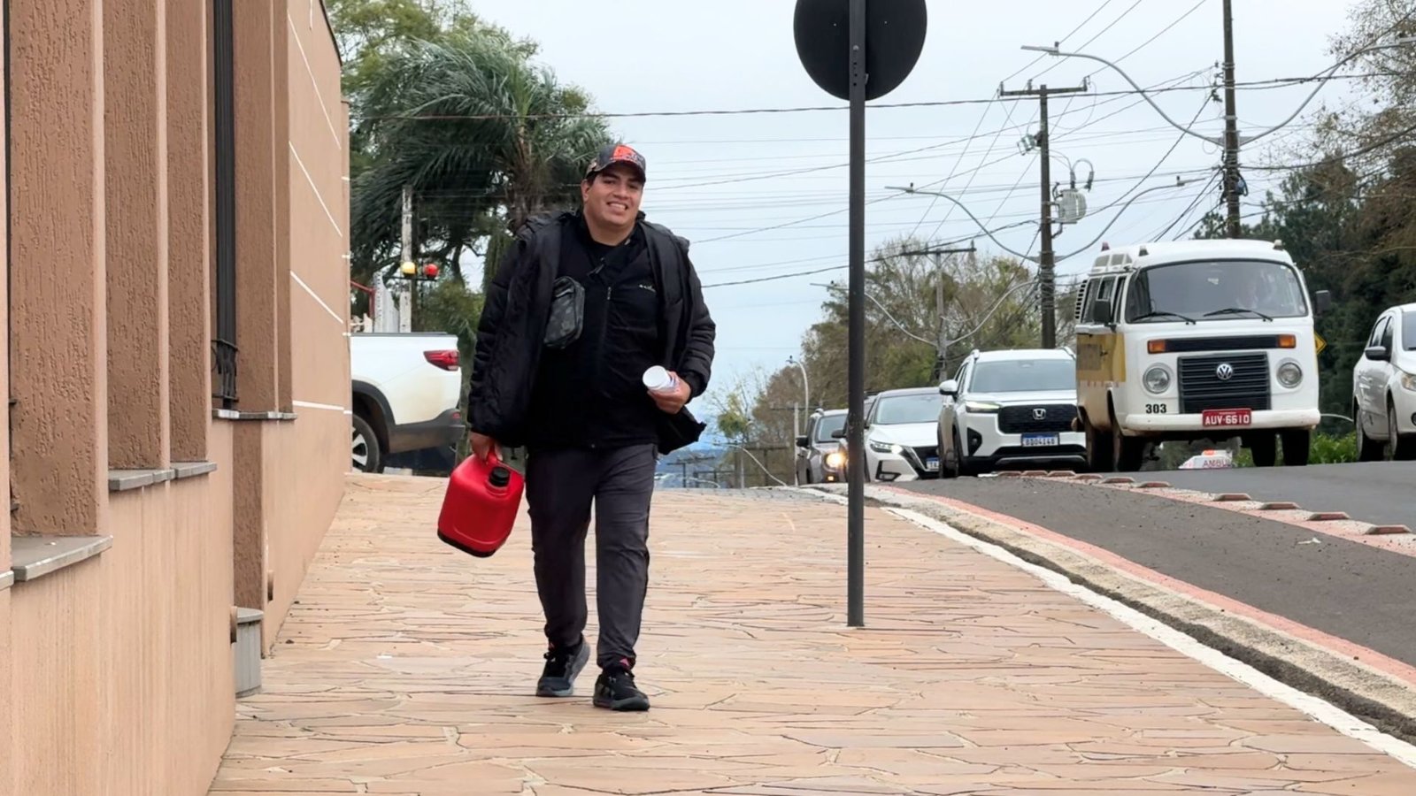 Gabriel oferecendo café a motoristas durante fechamento do semáforo na Avenida Manoel Ribas, em Guarapuava. Foto: William Batista/ Atento News