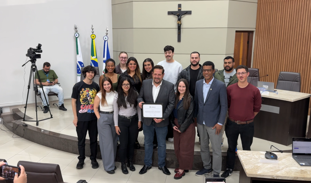 O secretário municipal de Comunicação de Guarapuava, Rafael Markus, acompanhado de integrantes da equipe da Secom e do vereador Nego Silvio, autor da proposta de homenagem, durante a entrega da moção de aplausos e congratulações na Câmara Municipal, nesta terça-feira (27). Fotos: William Batista/ Atento News